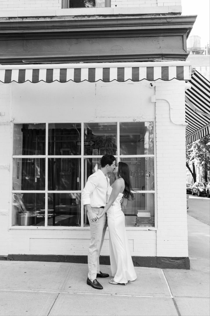 Leah and Jarryd kissing in front of a storefront, black and white