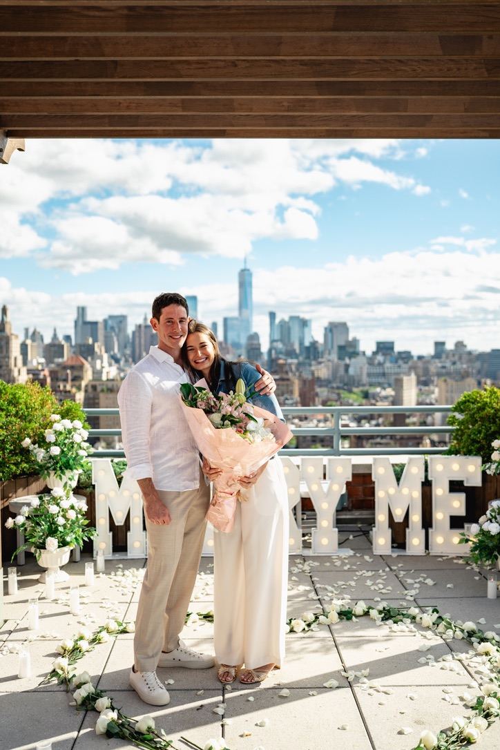 Leah and Jarryd hugging with a bouquet on the rooftop