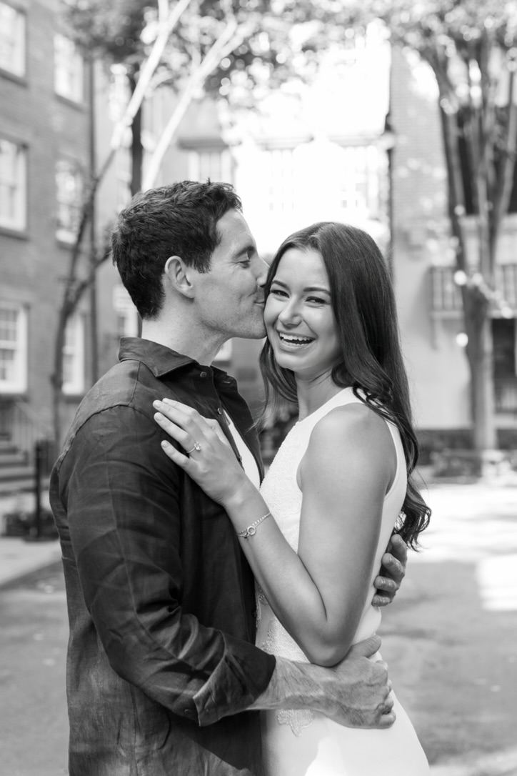 Jarryd kissing Leah on the cheek as she laughs, black and white