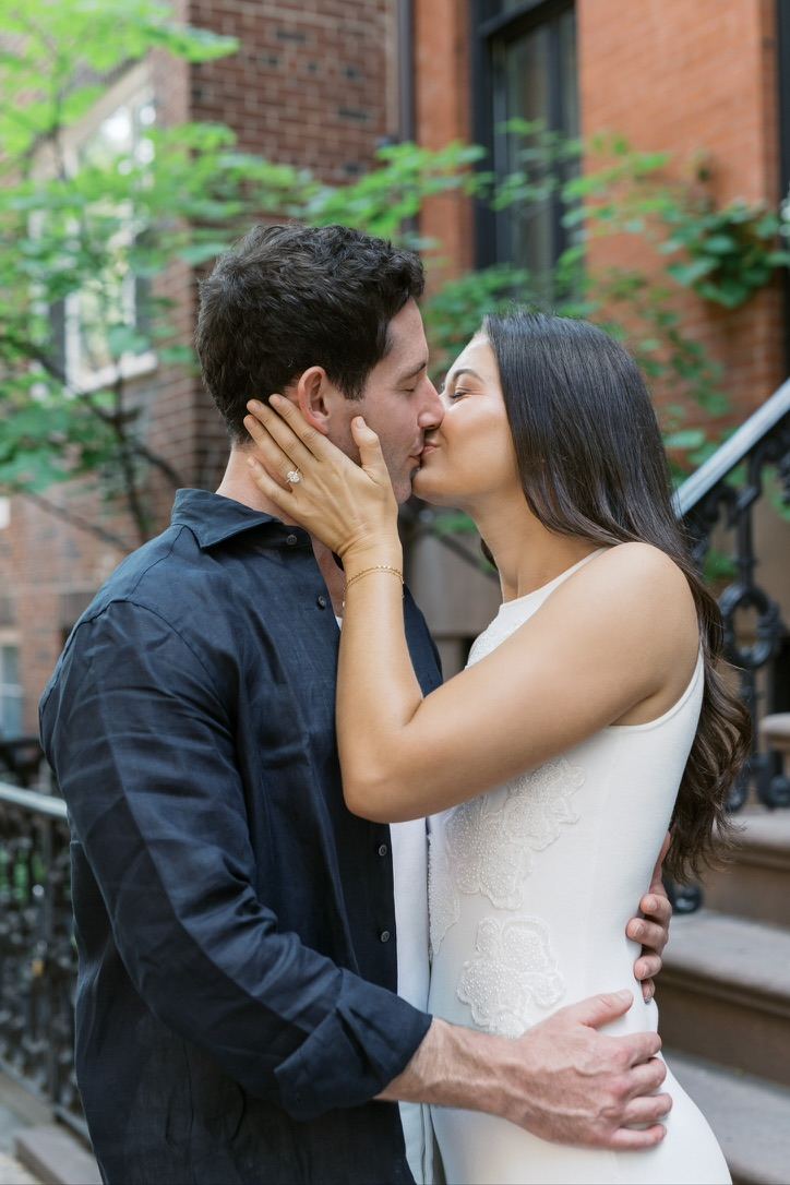 Leah and Jarryd kissing on a brownstone stoop